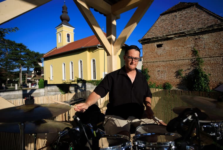 The drummer behind the kit in a vaulted venue